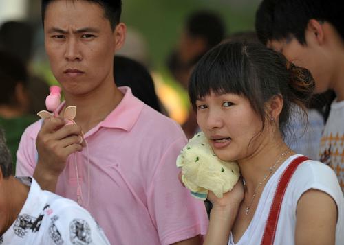 12 августа, посетители, стоящие в очереди перед Павильоном Германии в Парке павильонов ЭКСПО-2010 в Шанхае создают для себя прохладу с помощью полотенец и маленьких вентиляторов.