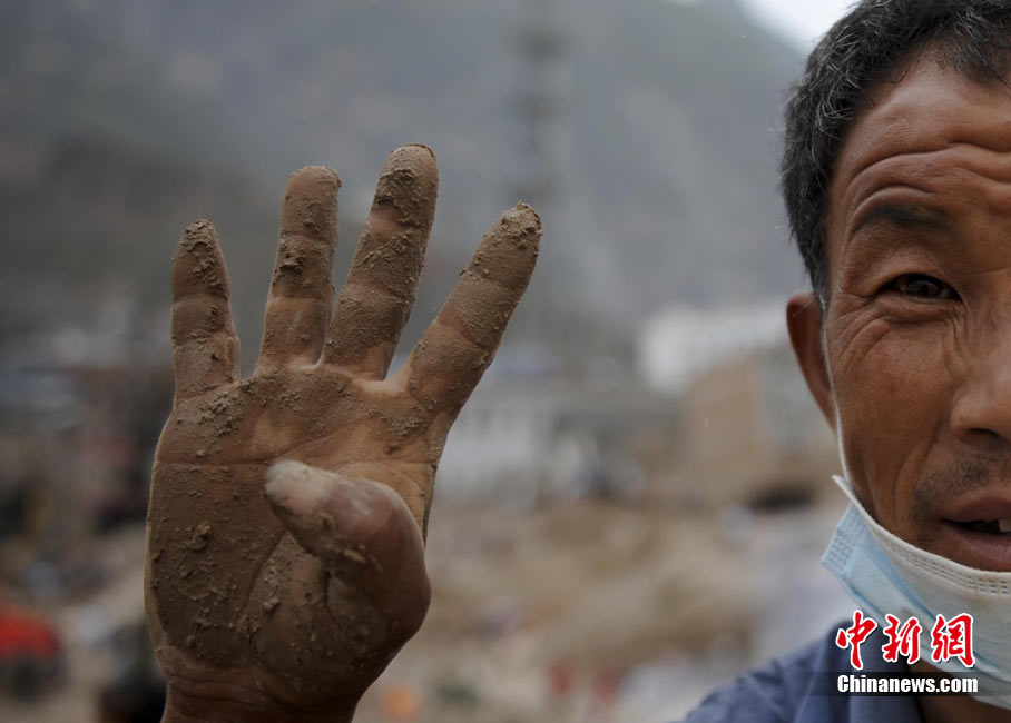 На фото: рука жителя в уезде Чжоуцюй, который собирает вещи погибших родственников. У него погибли 4 родственника.
