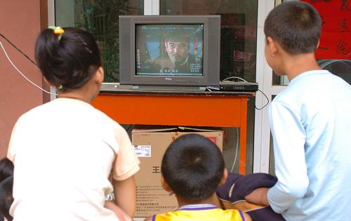 На фото: 16 августа 2010 года, в одном временном пункте жилья в первой средней школе уезда Чжоуцюй дети смотрят телевизор на открытом воздухе.