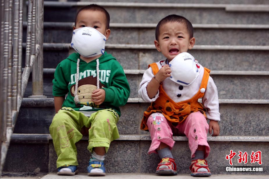 На фото:16 августа, в пострадавшем узеде Чжоуцюй годовалая девочка Ян Хуань (слева) и Лэлэ сидят на ступеньках. Одев большие медицинские маски, они ждут родственников. 