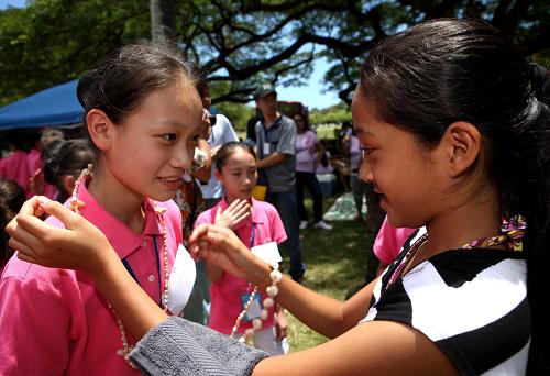 На фото: 28 августа, в Гонолулу США гавайская девочка (справа) подарила китайской подруге жемчужное ожерелье.