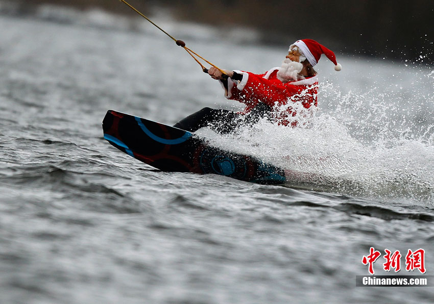 На фото: 5 декабря, один турист в костюме Санта-Клауса в Гамбурге Германии катается на водных лыжах в озере.