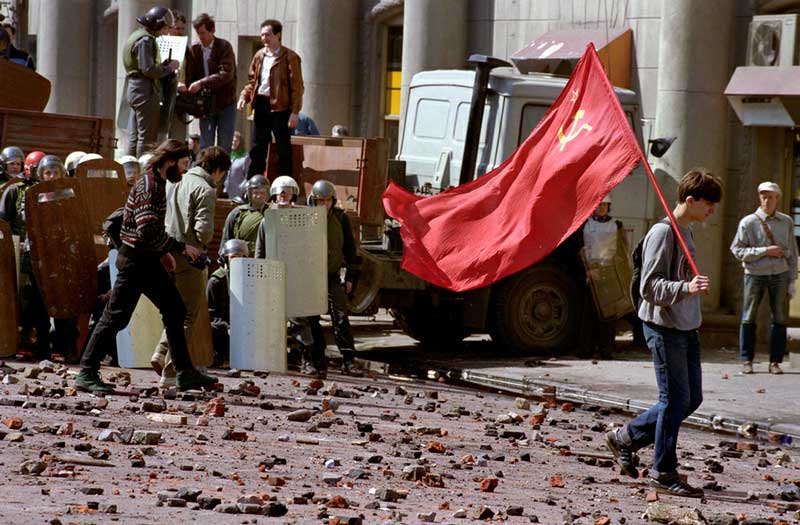 На фото: в 1993 году после столкновения милиции с народом, с флагом идет коммунист.