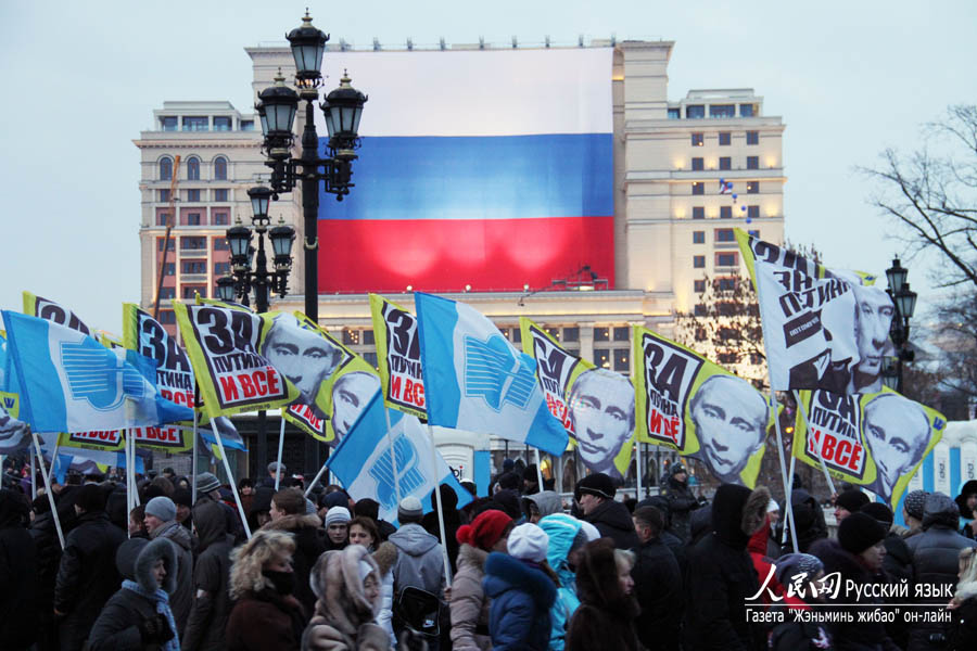 Собравшиеся на площади держали в руках флаги с символикой партии «Единая Россия» и портреты В. Путина. 