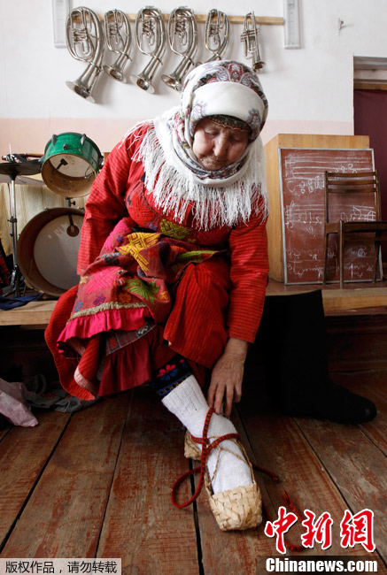 На фото: 15 марта, член российского коллектива «Бурановские бабушки» обувается.
