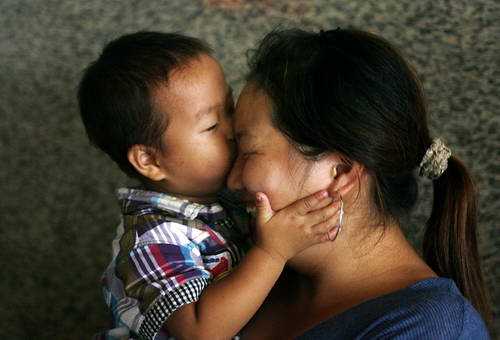 На фото: 21 августа в зале ожидания на вокзале г. Ханчжоу 2,5-летний мальчик И Юйцзе из провинции Хунань целует мать. После короткой встречи им нужно снова расставаться.
