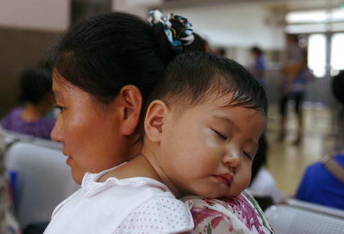 На фото: в зале ожидания на вокзале г. Ханчжоу годовалая девочка Мэнь Юйтун из провинции Хэнань уснула на плече матери.
