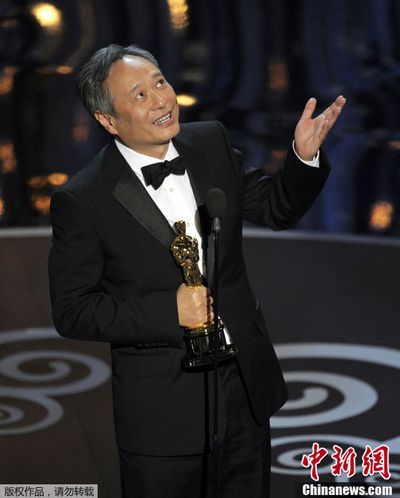 Счастливый режиссер Ли Ань ест гамбургер на улице, держа «Оскара» в руке 