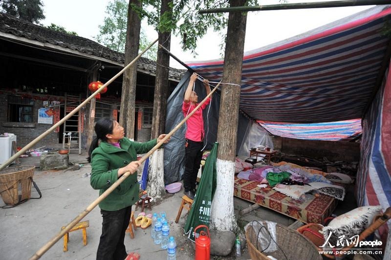 На фото: в деревне Гучэн уезда Лушань, Ло Чи на открытом пространстве перед домом устанавливает палатку.