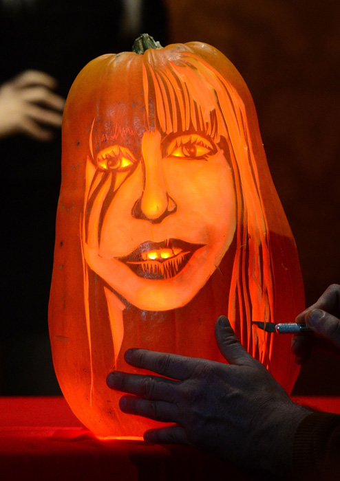 22 октября в Музее мадам Тюссо в Нью-Йорке мастер по резке из тыквы Хью МакМагон сравнивает свою работу с восковой фигурой Леди Гага.