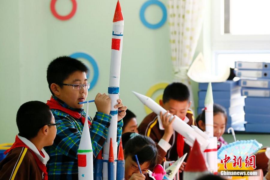 2 декабря школьники начальной школы центра Эрлигоу района Хайдянь г.Пекин раскрашивают разными цветами модели спутника зондирования Луны «Чанъэ-3» и китайского лунохода «Юйту». 