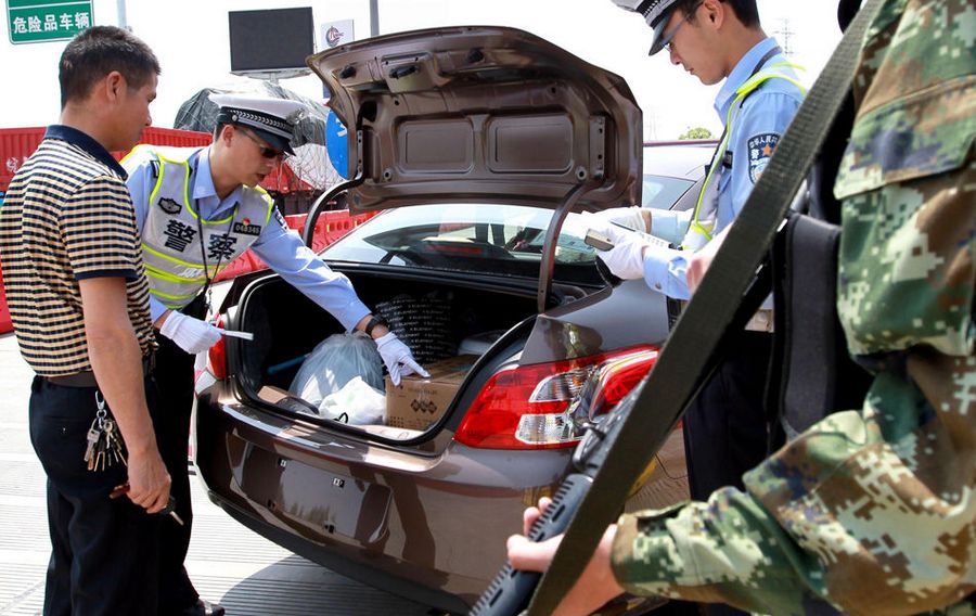 На фото: 15 мая в пункте оплаты скростной автодороги «Чжуцяо» полицейские района Цзядин г.Шанхай проводят досмотр багажника автомобиля.