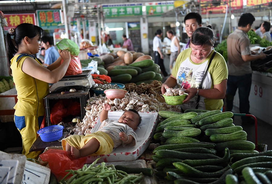 На сельскохозяйственном рынке в г. Наньнин Гуанси-Чжуанского автономного района многие дети проводят свои каникулы вместе с родителями, которые торгуют там.