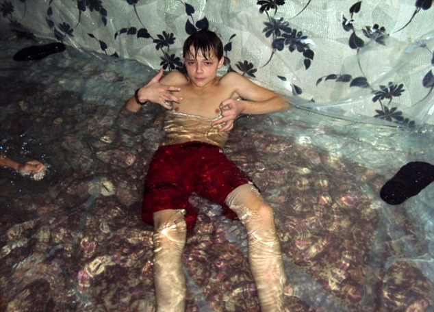 На фото: мальчики плавают и ныряют в самодельном бассейне из гостиной, мебель и батарея покрыты слоем пластиковой пленки.