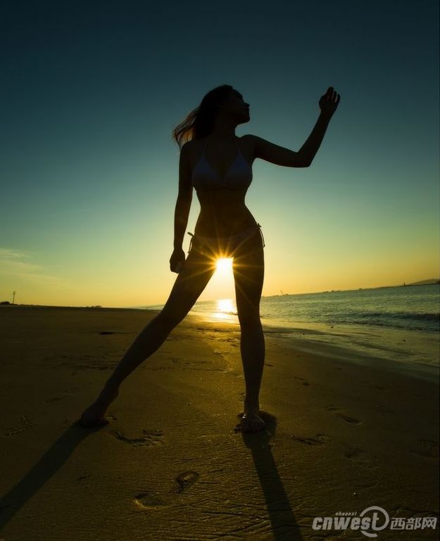 Красавица на пляже показывает прекрасную фигуру под утренним солнцем