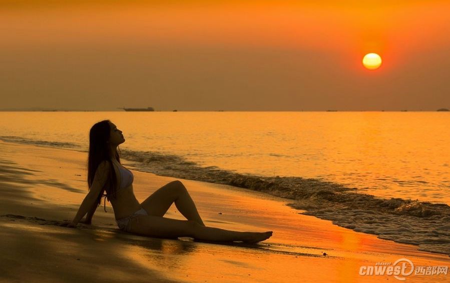 Красавица на пляже показывает прекрасную фигуру под утренним солнцем