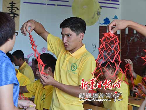 Студент из Кыргызстана Нурлан демонстрирует гирлянду, сделанную при помощи китайского искусства вырезания по бумаге - цзяньчжи.