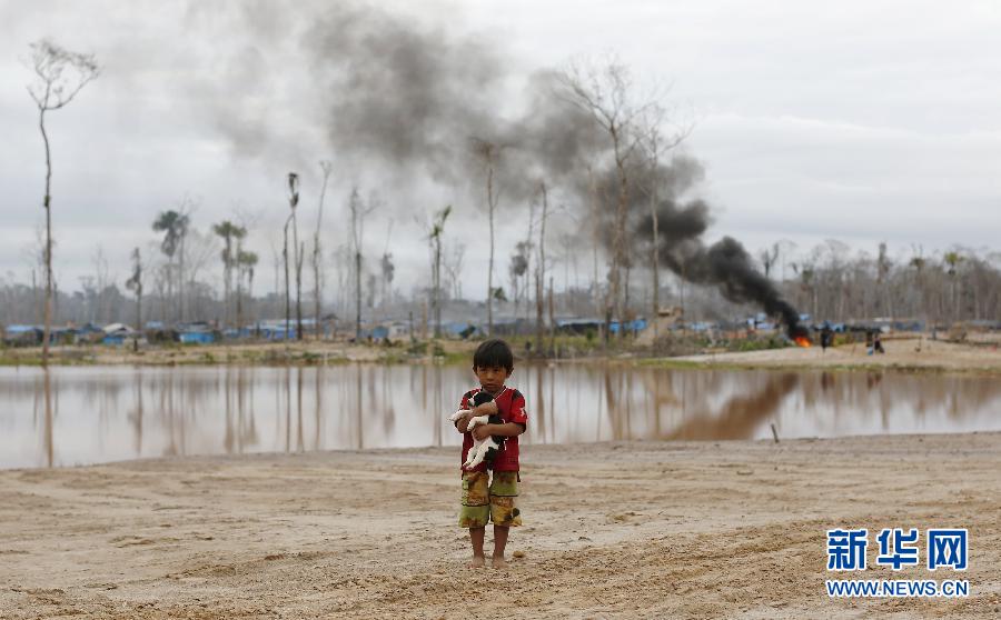 На фото: 14 июля в Перу, перед нелегальным золотым рудником стоит мальчик.