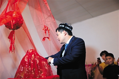 Жених накрывает голову невесты красным шарфом, однако на глазах у невесты еще одна красная повязка.