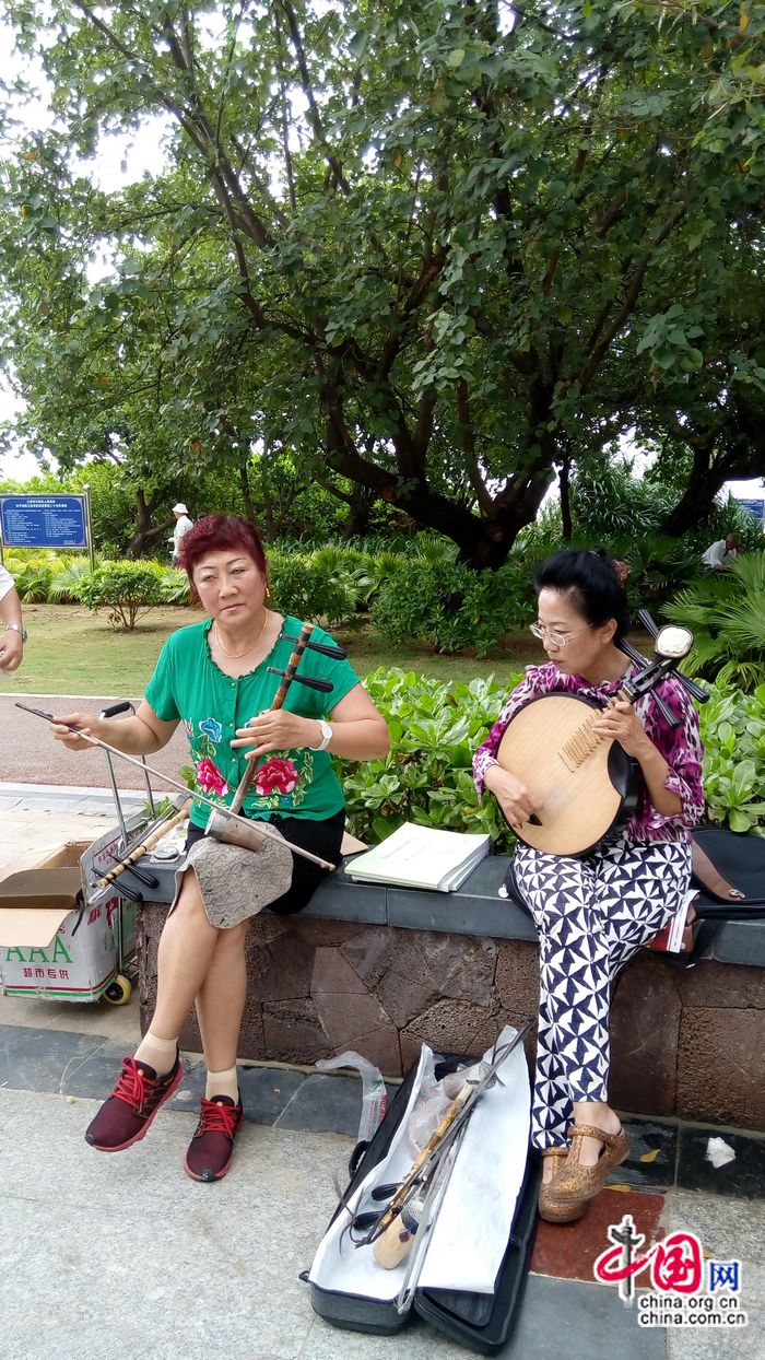 Тетушка Сюй (справа) аккомпанирует актерам-любителям во время репетиции Пекинской оперы под открытым небом на Хайнане.