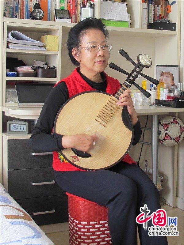 Тетушка Сюй дома в Пекине играет на юецине.