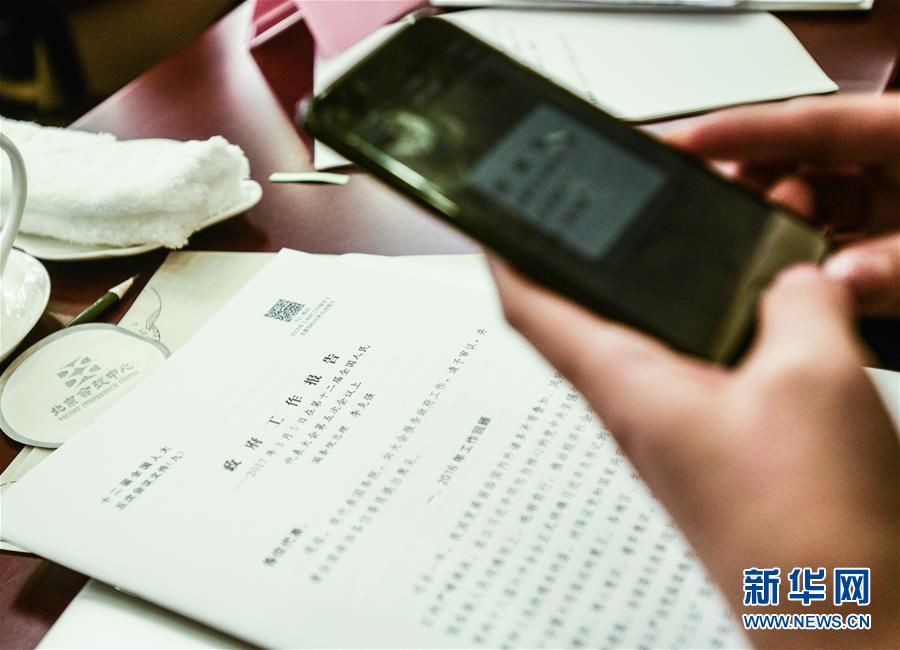 На фото: 5 марта в Пекинском конференц-центре корреспондент для получения информации сканирует двухмерный штрих-код, который напечатан в тексте «Доклада о работе правительства Китая».