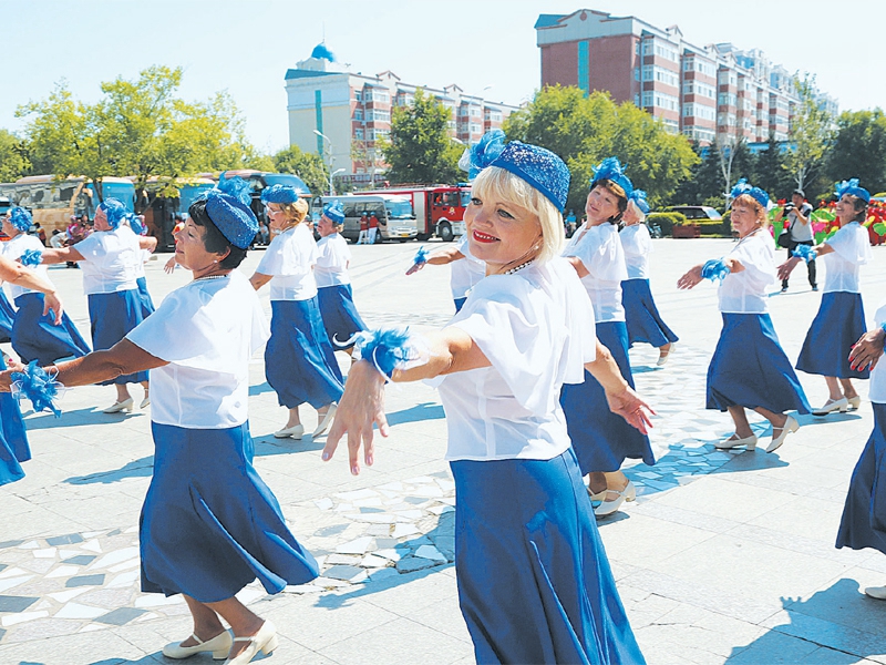 Пожилые люди из Китая и России танцуют на площади г. Хэйхэ 