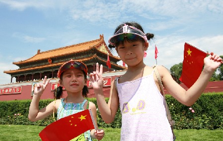 Dos niños, con banderas nacionales en la mano, posan para una fotografía en la plaza Tian’anmen. La bandera nacional de China es roja y contiene cinco estrellas y la capital es Beijing.