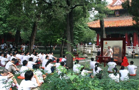 Un profesor de universidad enseñando la cultura confuciana en el Templo de Confucio, con los oyentes sentados en el suelo, deleitados por la clase.