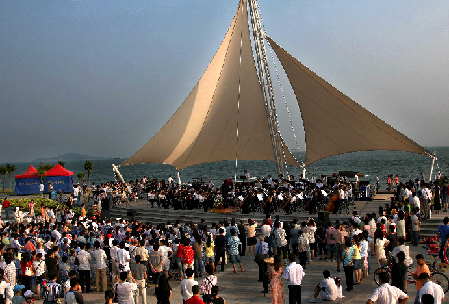 Gran concierto al aire libre presentado por una orquesta en la ciudad de Xiamen, atrayendo a muchos amantes de la música.