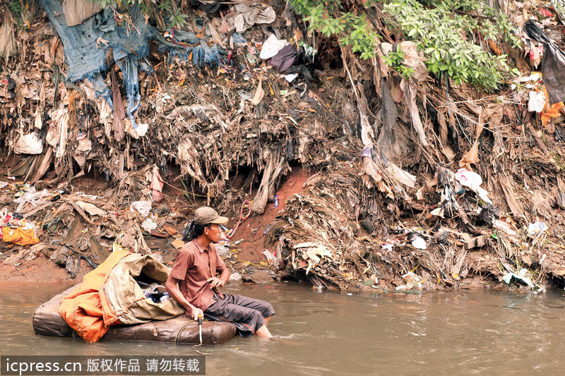 Un hombre cogió las basuras sentaba en ‘barco flotante’ hecho por basuras 一名男子坐在用垃圾做的浮舟上捡垃圾。