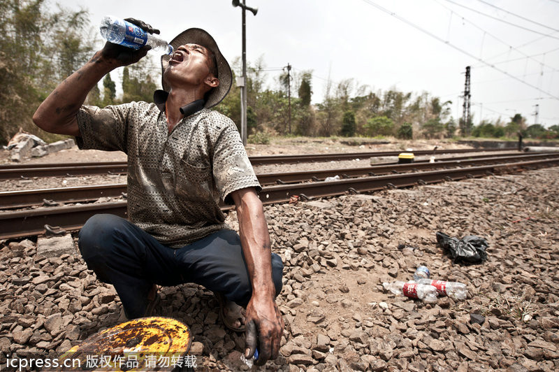 Un obrero estaba bebiendo al lado del ferrocarril 一名工人蹲在鐵軌旁喝水。