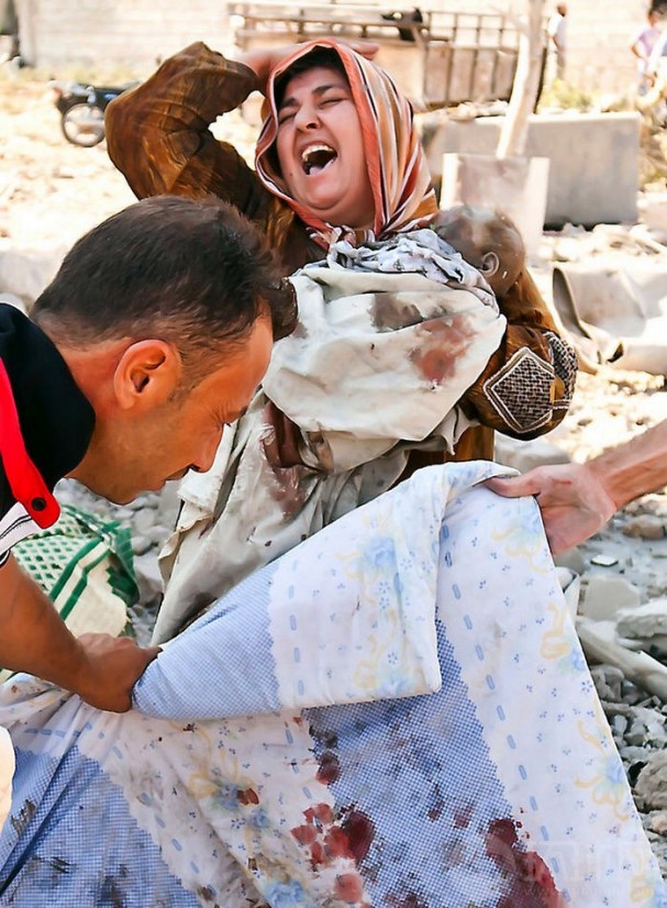El día 15 de agosto de 2012 en Azaaz, Siria, una mujer lloraba abrazando a su niño muerto cuando miraba a su marido muerto.