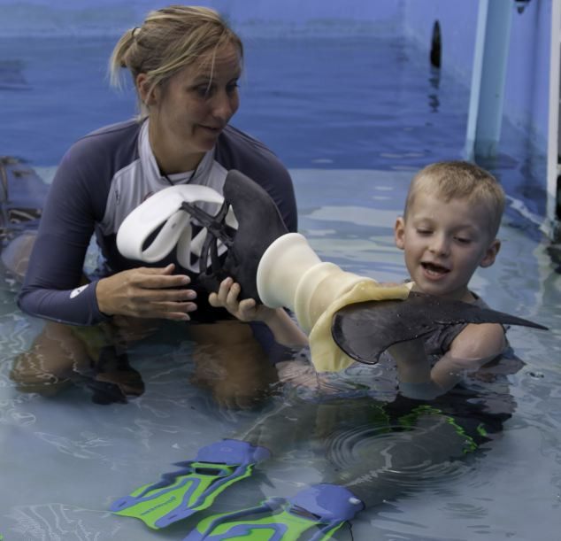 Niños de 8 años quien perdió las dos piernas nada con un delfin