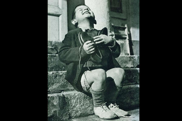 En 1946 la Cruz Roja Americana llegó a Austria y regaló un par de zapatos a Werfel, un niño de 6 años que vivía en un orfanato, feliz los recibe y abraza. Esta fotografía fue publicada por la revista Life.