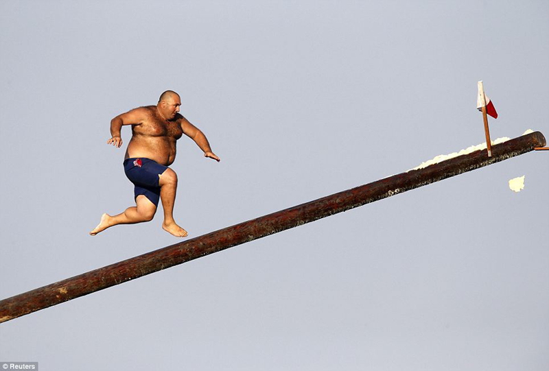 Un hombre corre sobre un palo cubierto de grasa durante la celebración de la fiesta de San Julián, patrono de St Julian, en Malta, el 25 de agosto.