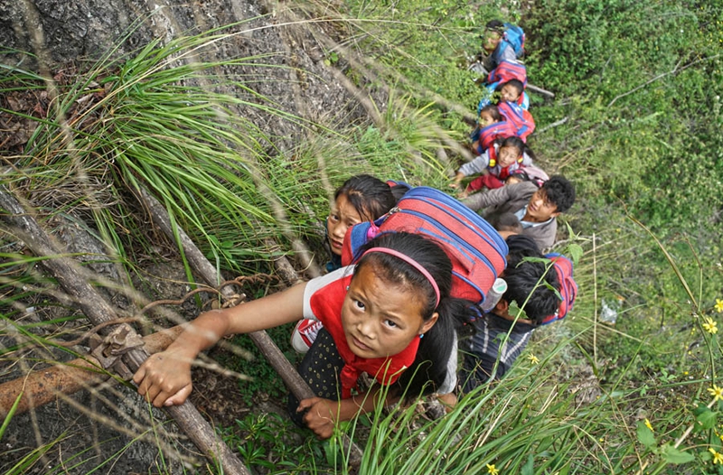 Unos niños escalan un acantilado de 800 metro en el camino a la escuela