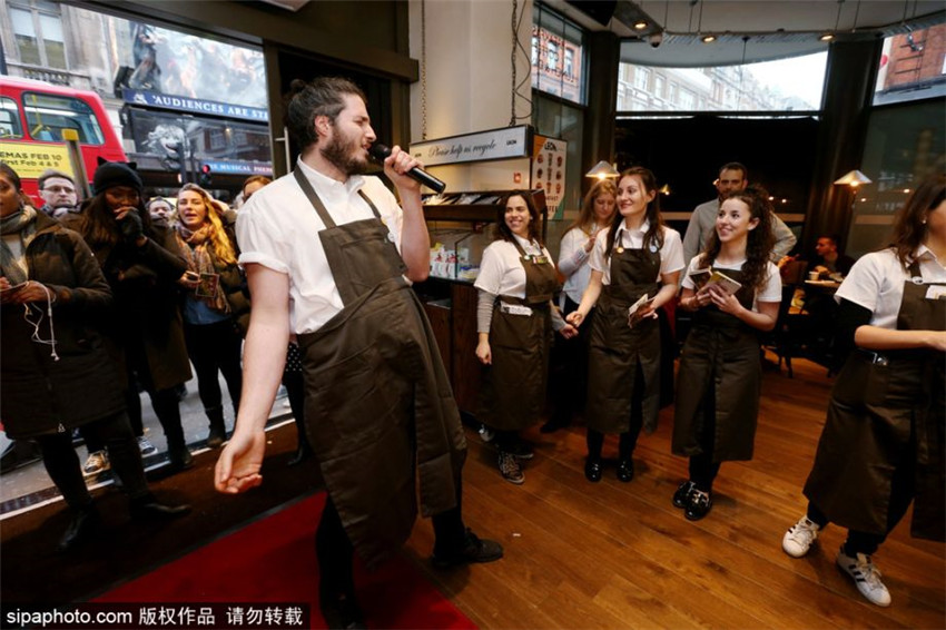 Camareos de un restaurante londinense cantan al servir comidas y bebidas