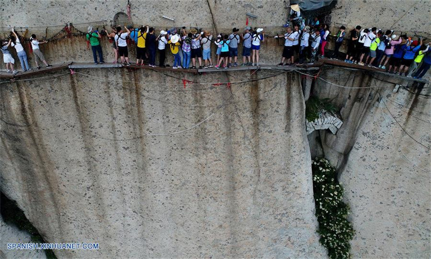 Turistas caminan sobre un camino de tablones construido sobre un acantilado, en la montaña Huashan en Huayin, provincia de Shaanxi, en el noroeste de China, el 14 de julio de 2017. La temporada alta comenzó en el área escénica cuando un gran número de turistas viene a visitar la montaña Huanshan en el verano. 