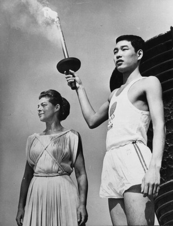 Yoshinori Sakai, born at Hiroshima on the day the first atomic bomb was dropped on the city, holding the Olympic torch beside Greek actress Aleka Katseli during a rehearsal for the opening ceremony of the Olympic Games at Tokyo.