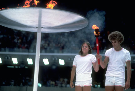 The last torch bearers, Sandra Henderson and Stephane Prefontaine, stand in front of the lit cauldron at the opening ceremony of Montreal 1976 Olympic Games, in Montreal, Canada, on July 17, 1976.