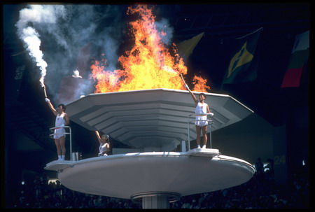 Torchbearers turn to salute the crowd after lighting the Olympic Flame during the opening ceremony of the 1988 Seoul Olympics.