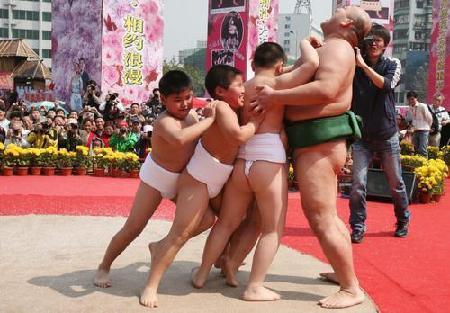 Children challenge a Japanese sumo wrestler during a show at Guangzhou Sculpture Park, on Sunday, March 2, 2008. 