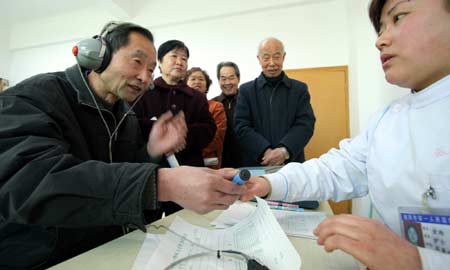 An aurist examines the ears for an old man at No. 1 People’s Hospital in Xianyang, northwest China's Shaanxi Province, Mar. 3, 2008, the day of the ninth National Ear Health Care Day.