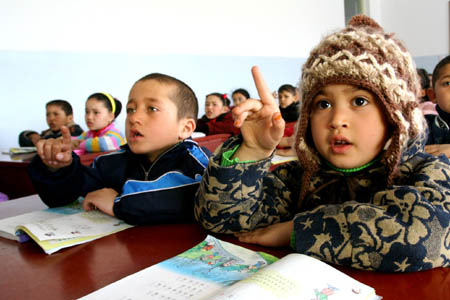 Pupils from families of poverty attend class with free textbooks at a school of Division 5 of Xinjiang Production and Construction Corps in Bole, northwest China's Xinjiang Uygur Autonomous Region, March 3, 2008. About 17,000 pupils of Division 5 were offered free textbooks from the government as the new term started. (Xinhua/Shen Zhijun)