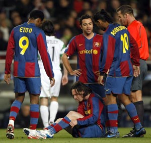 Barcelona's Lionel Messi sits injured on the pitch as his team mates watch during their Champions League first knockout round, second leg soccer match against Celtic in Barcelona March 4, 2008.
