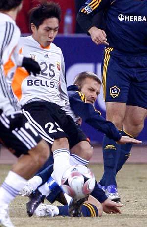 Los Angeles Galaxy's David Beckham (bottom) fights for the ball during a soccer match performance against Shanghai Hong Kong United in Shanghai, east China, March 5, 2008. Los Angeles Galaxy won 3-0.