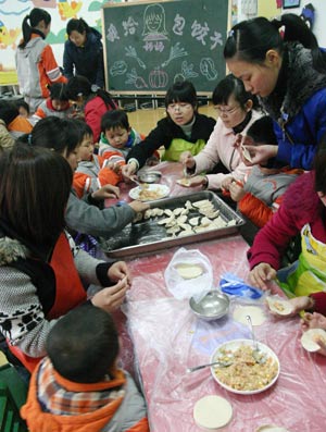  Children wrap dumplings together with their moms at the Golden Dock Bilingual Art Kindergarten in Caohu, east China's Anhui Province, March 6, 2008. The kindergarten carries out mother-child affinity activities, namely Feeding Mom Dumplings and Wrapping Dumpling for Mom, bestowing the children the empathy for mom's swink and their gratitudes for moms through labor by themselves.