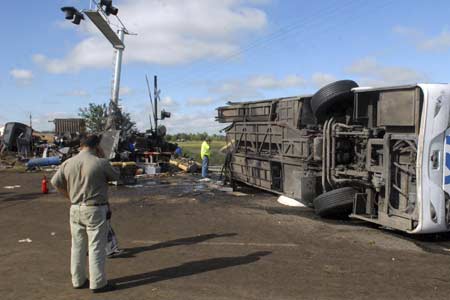 People talk on their phones while inspecting the wreckage at the rail crossing where a passenger train crashed into a bus in Dolores, Buenos Aires province March 9, 2008. 