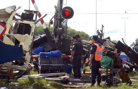 Policemen walk near the rail crossing where a passenger train crashed into a bus in Dolores, Buenos Aires province March 9, 2008. A train crashed into a bus in Argentina early on Sunday, killing 18 people and injuring about 45, local media reported. "It seems the driver of the bus passed when the barrier was down and the train cut the bus in half," Daniel Scioli, the provincial governor, told local television at the crash scene.